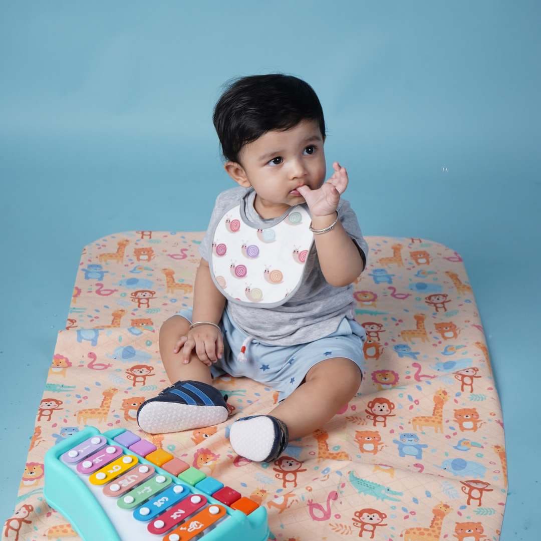 baby-wearing-bib-sitting-on-crib-sheet
