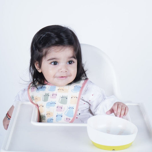 Baby-wearing-printed-bib-while-sitting-on-chair