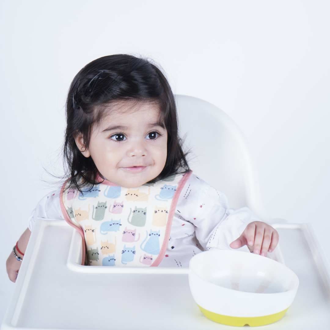 Baby-wearing-printed-bib-while-sitting-on-chair