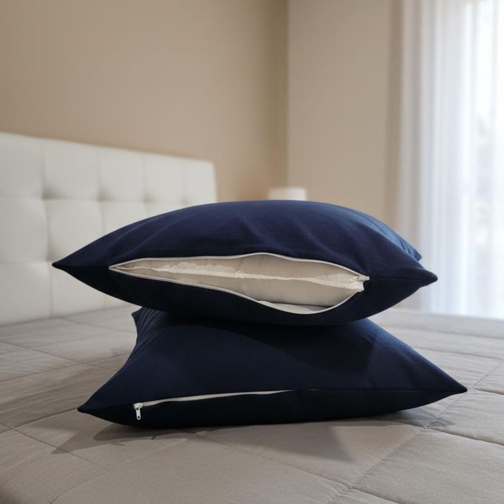Two navy blue pillowcases stacked on a bed, with the top one slightly open to show a white interior lining.