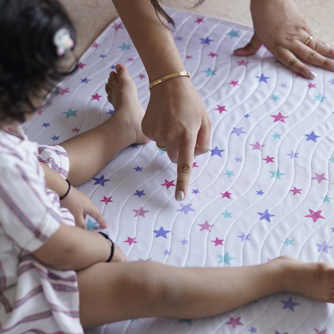 Baby-sitting-on-playmat-hand-pointing-to-stars