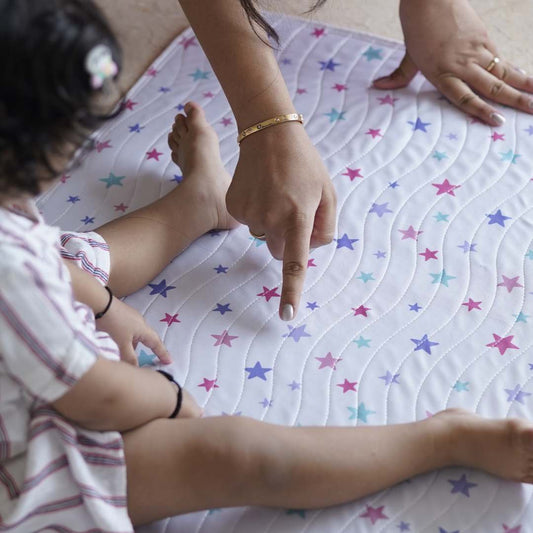 Baby-sitting-on-playmat-hand-pointing-to-stars