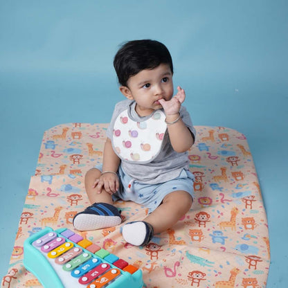 Baby-sitting-on-crib-sheet-wearing-bib