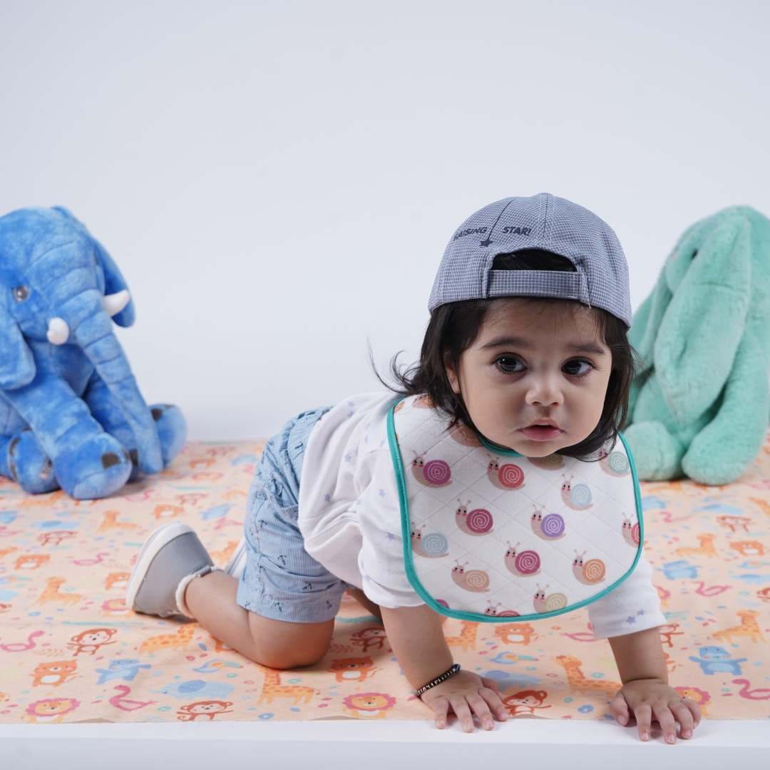 Kid-wearing-printed-bib-and-crawling-on-crib-sheet