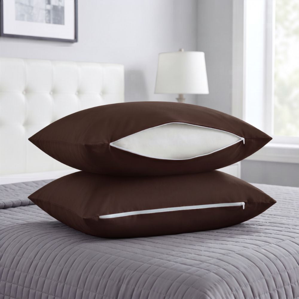 Two brown pillowcases stacked on a gray quilted bedspread in a bedroom setting, with one pillowcase open to show a white insert.