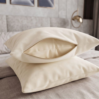 Two cream-colored pillowcases stacked on a bed, with the top one slightly open to show the interior lining.