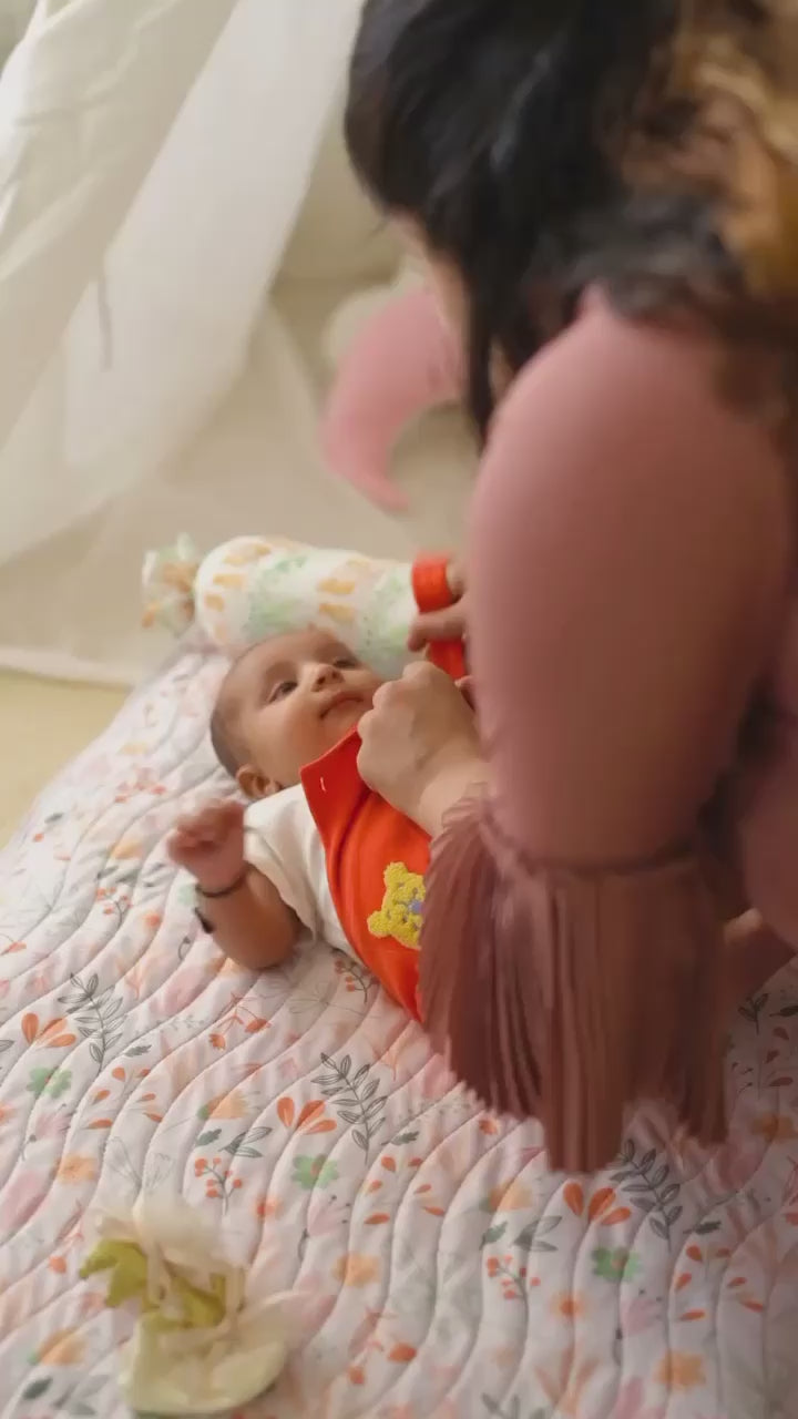 Mother dressing her baby on a mat